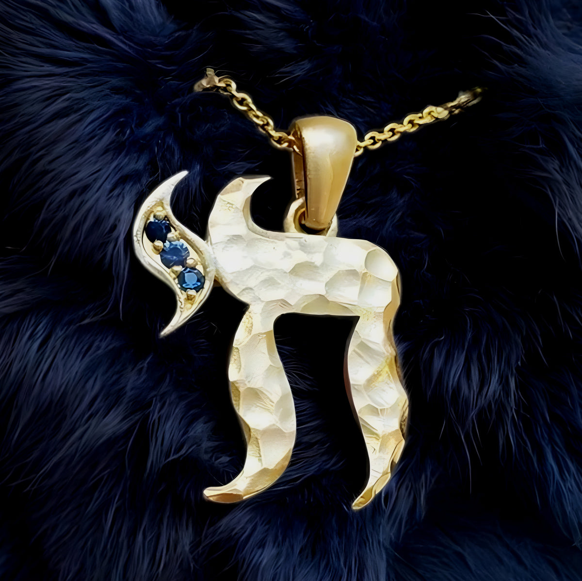 Gold pendant with blue stones on a dark fur background