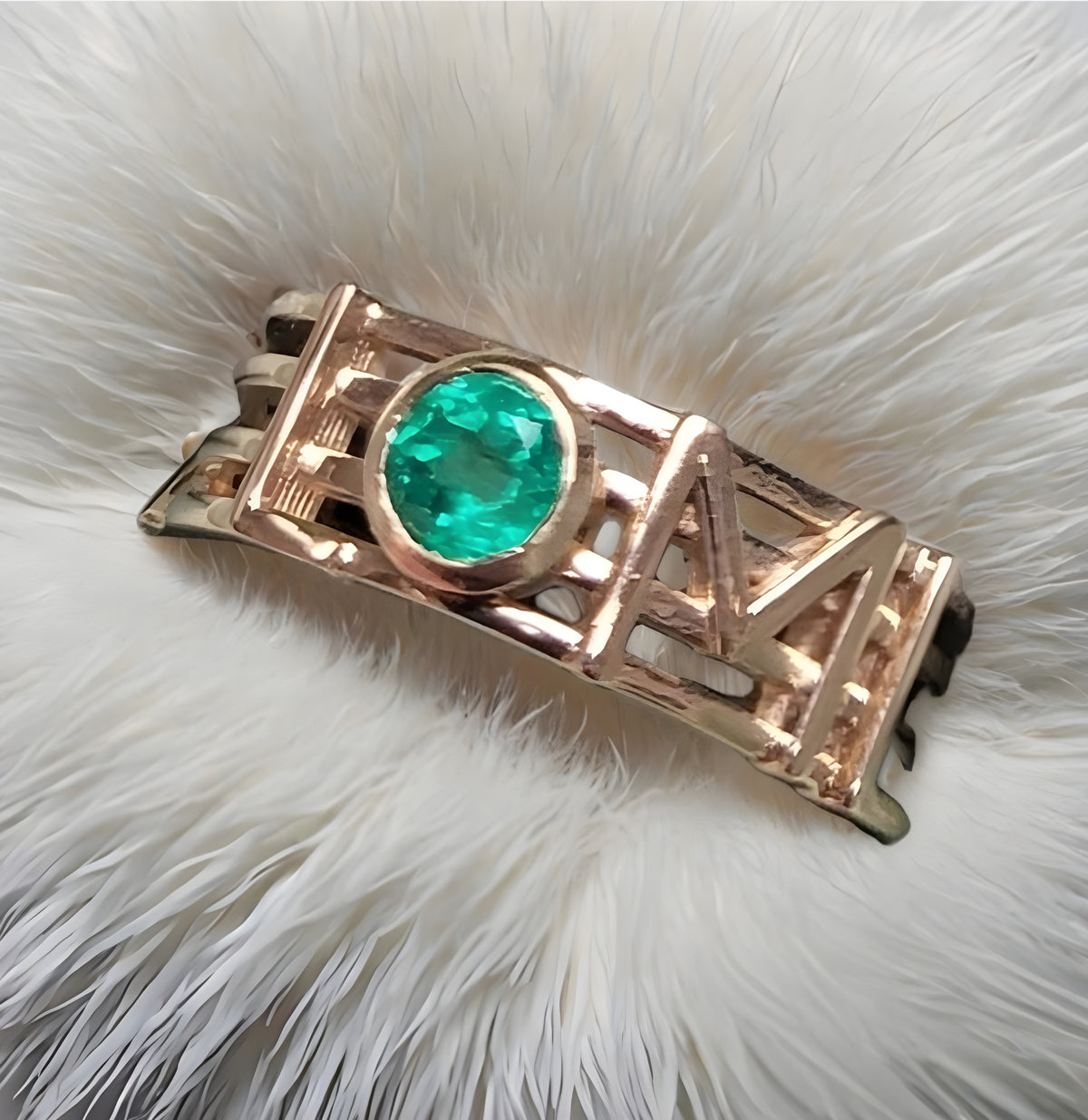 Rose gold ring with a green gemstone on a white fur background