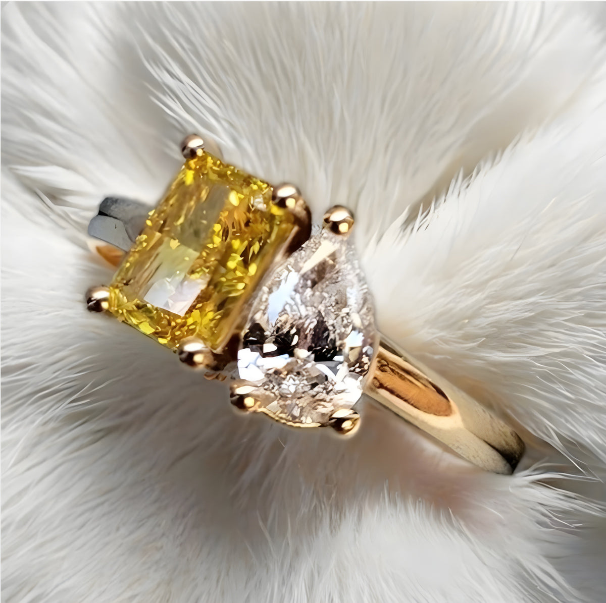 Gold ring with yellow and clear gemstones on a white fur background