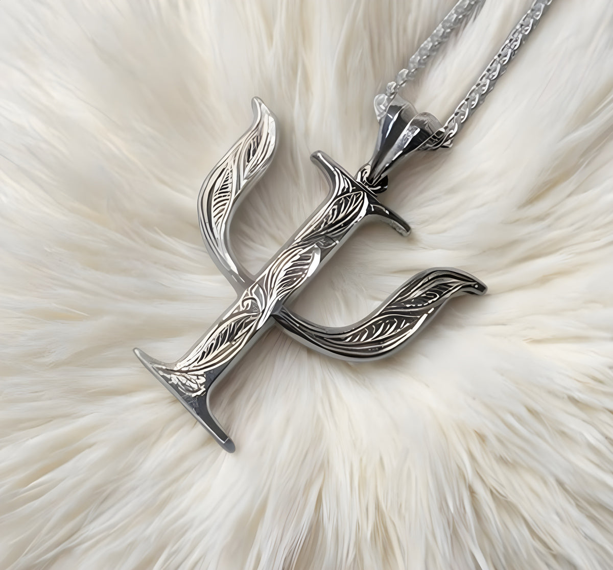 Silver greek pendant with intricate design on a white fur background