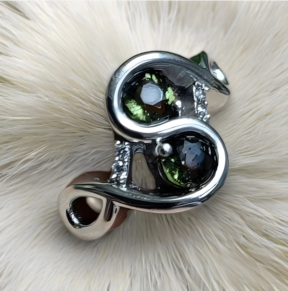 Silver and green gemstone brooch on a white fur background