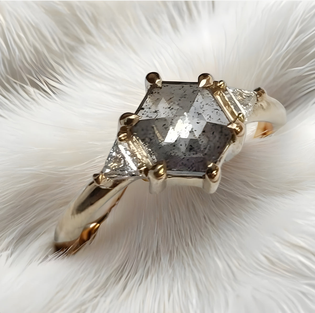 Gold ring with a large diamond on a white feather background