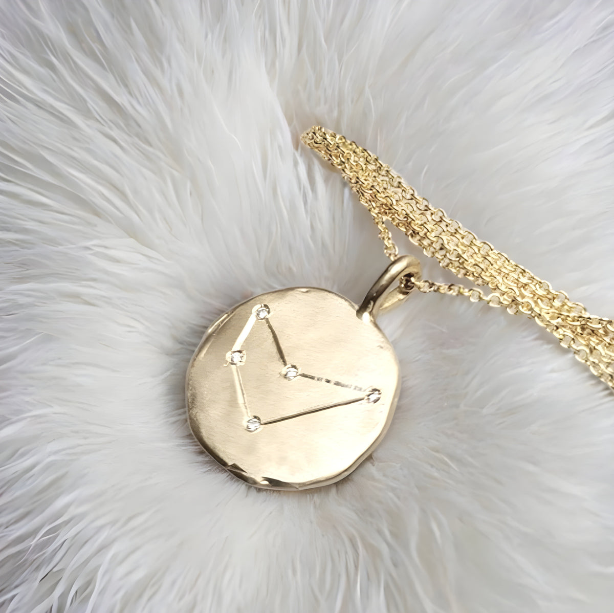 Gold necklace with a circular pendant on a white fur background
