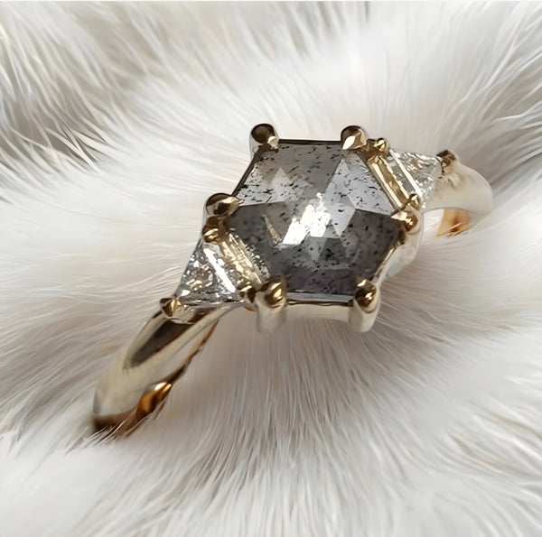 Gold ring with a large diamond on a white feather background