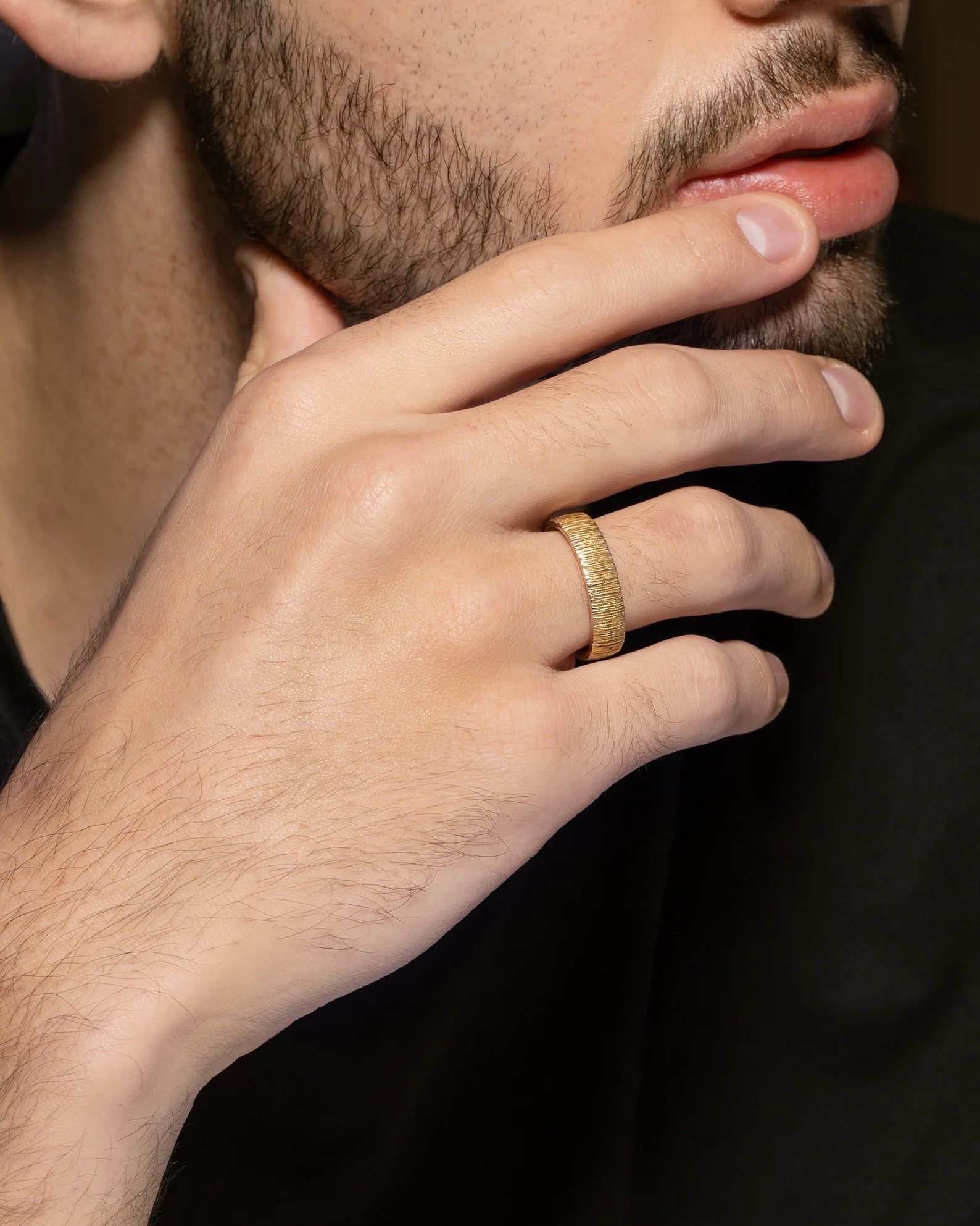 Close-up of a hand wearing a gold ring with a blurred background