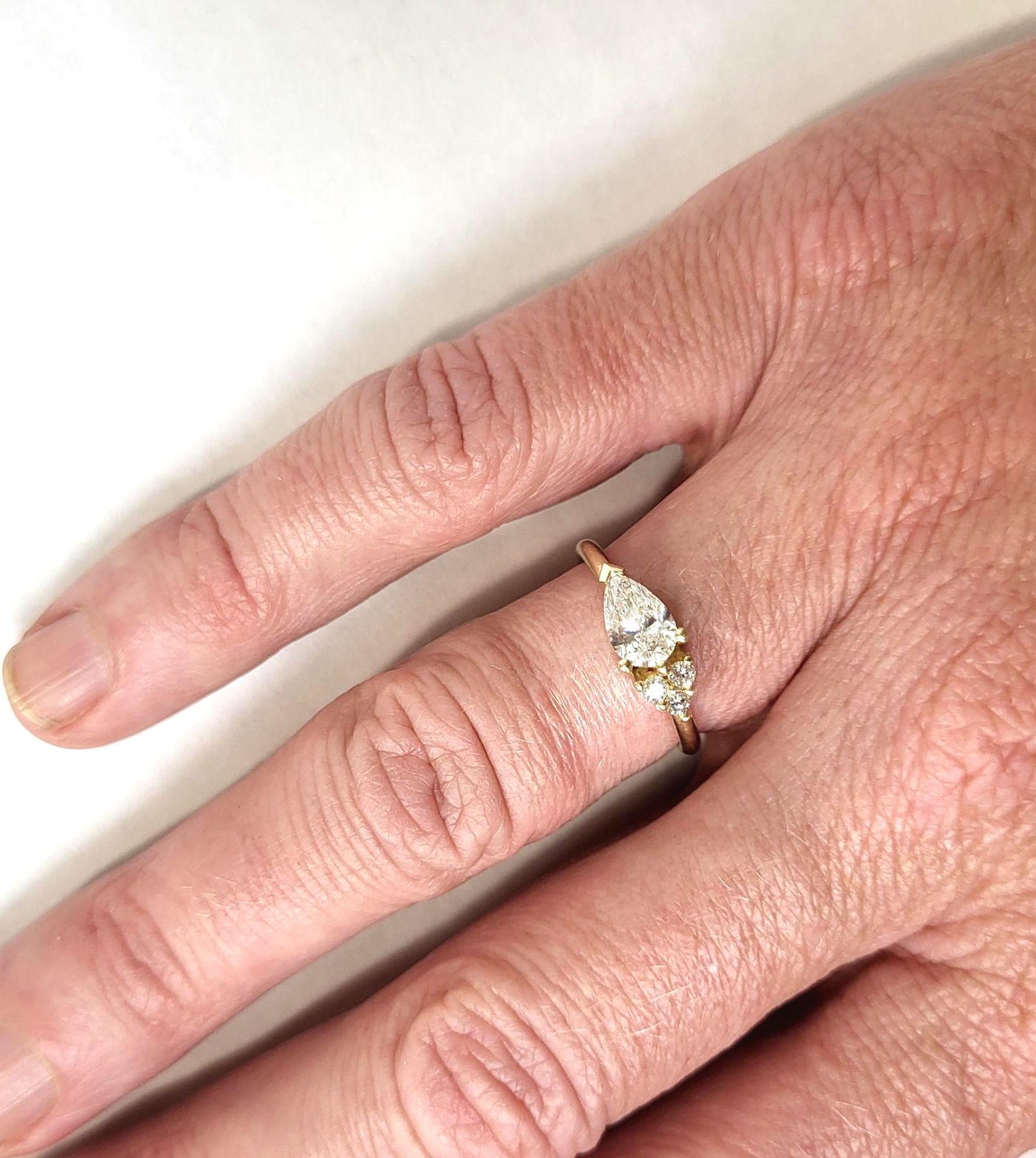 Bague en or jaune, rose ou blanc, sertie d'un diamant de synthèse taille poire, serti latéral, avec un diamant accentué.